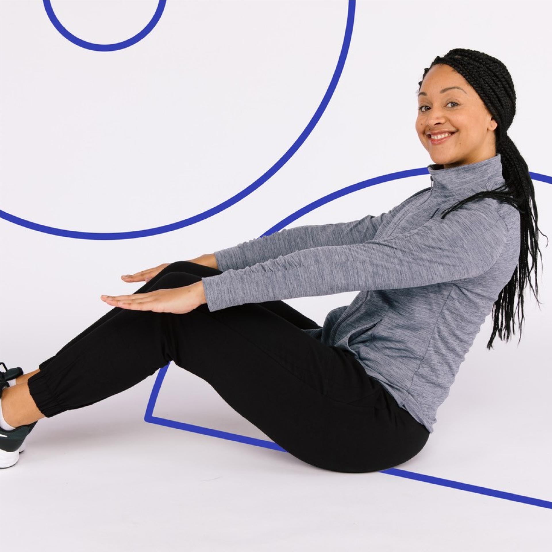 A woman sat down smiling to camera with arms and legs out