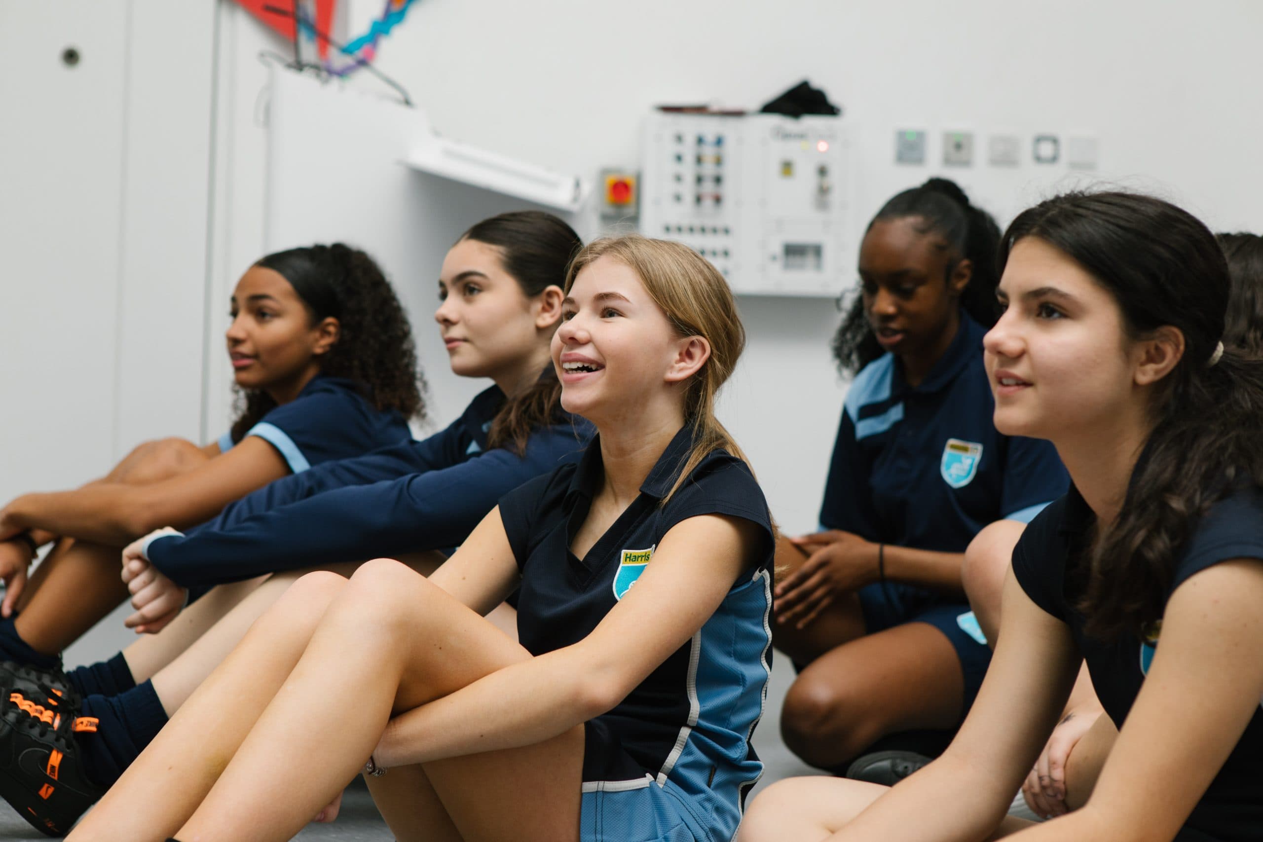 A group of teenage girls sat down in a PE class listening